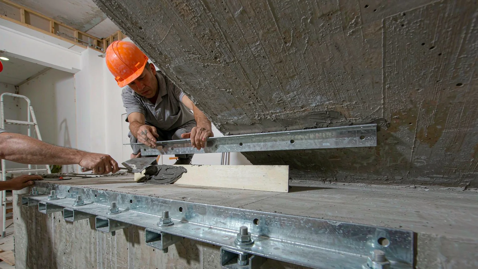 建筑梁底粘钢加固施工现场，工人涂胶并压贴钢板
